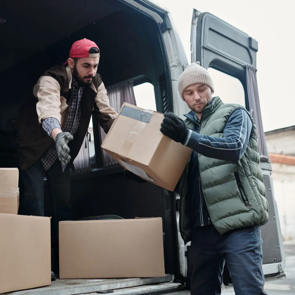 Dos transportistas cargando cajas a un furgón
